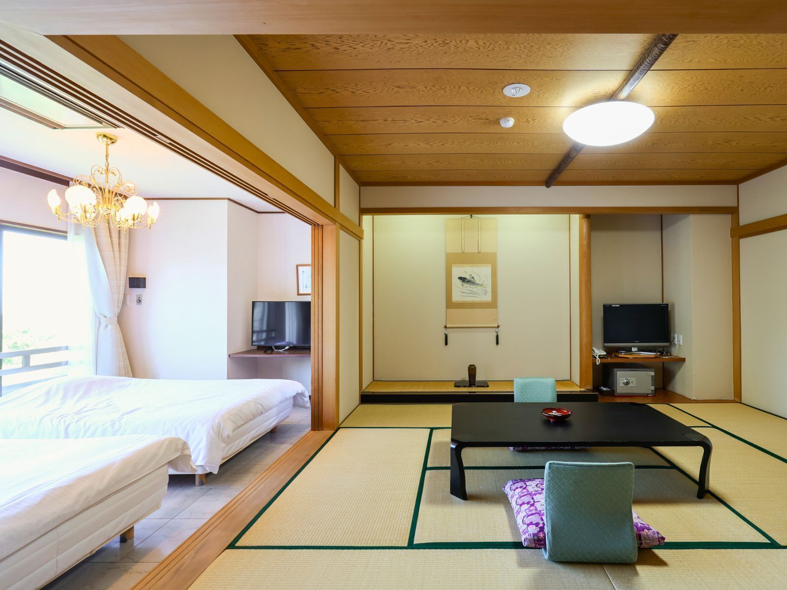Una habitación al estilo japonés tradicional con suelo de tatami, una cama, un escritorio con televisor y una puerta corrediza.