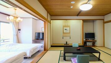 Una habitación al estilo japonés tradicional con suelo de tatami, una cama, un escritorio con televisor y una puerta corrediza.