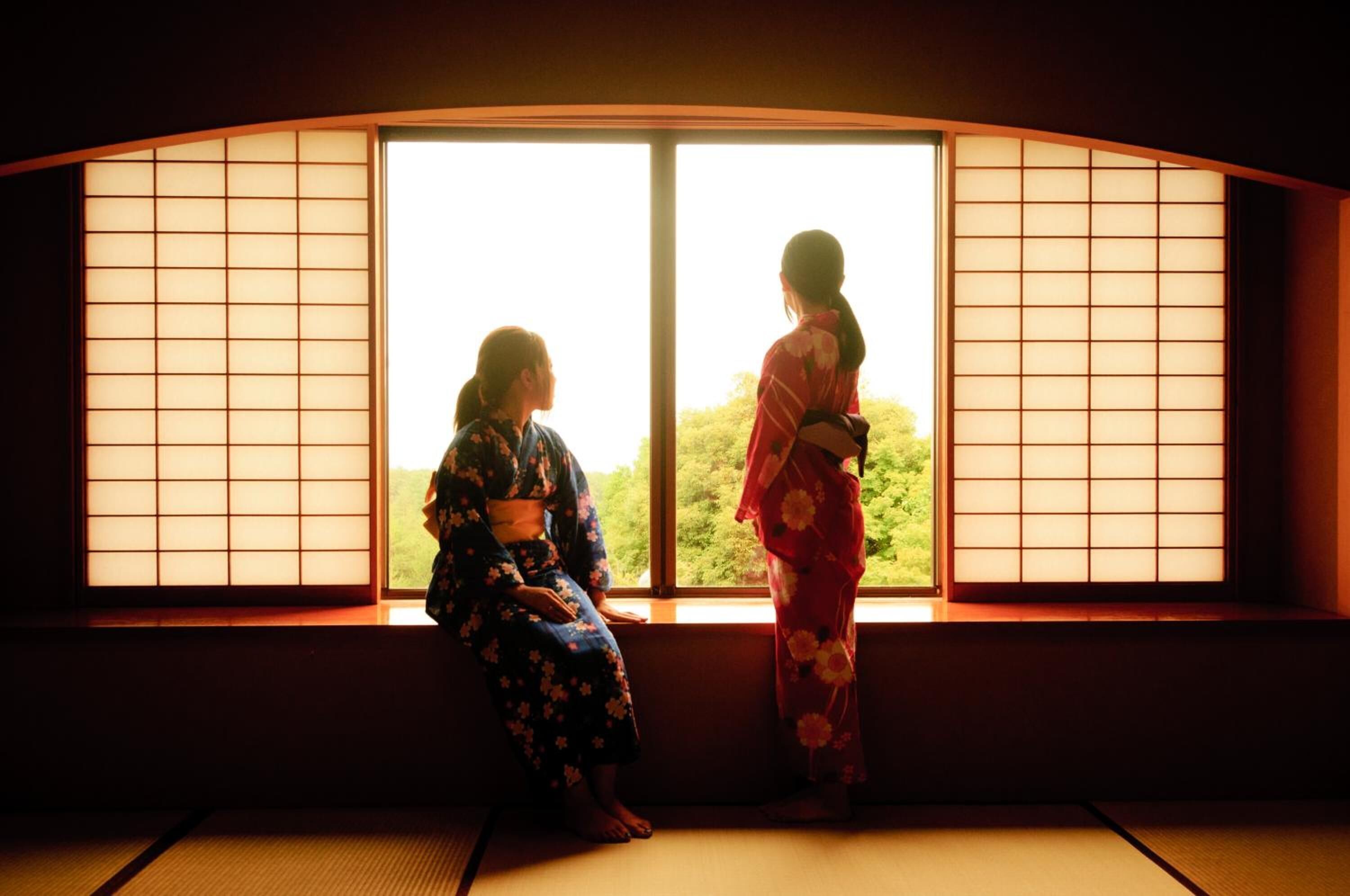 Two people sitting by a window with traditional Japanese sliding doors.