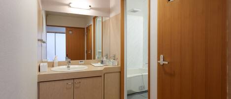 A modern bathroom with a large mirror, two sinks, wooden cabinets, and a glass shower enclosure.