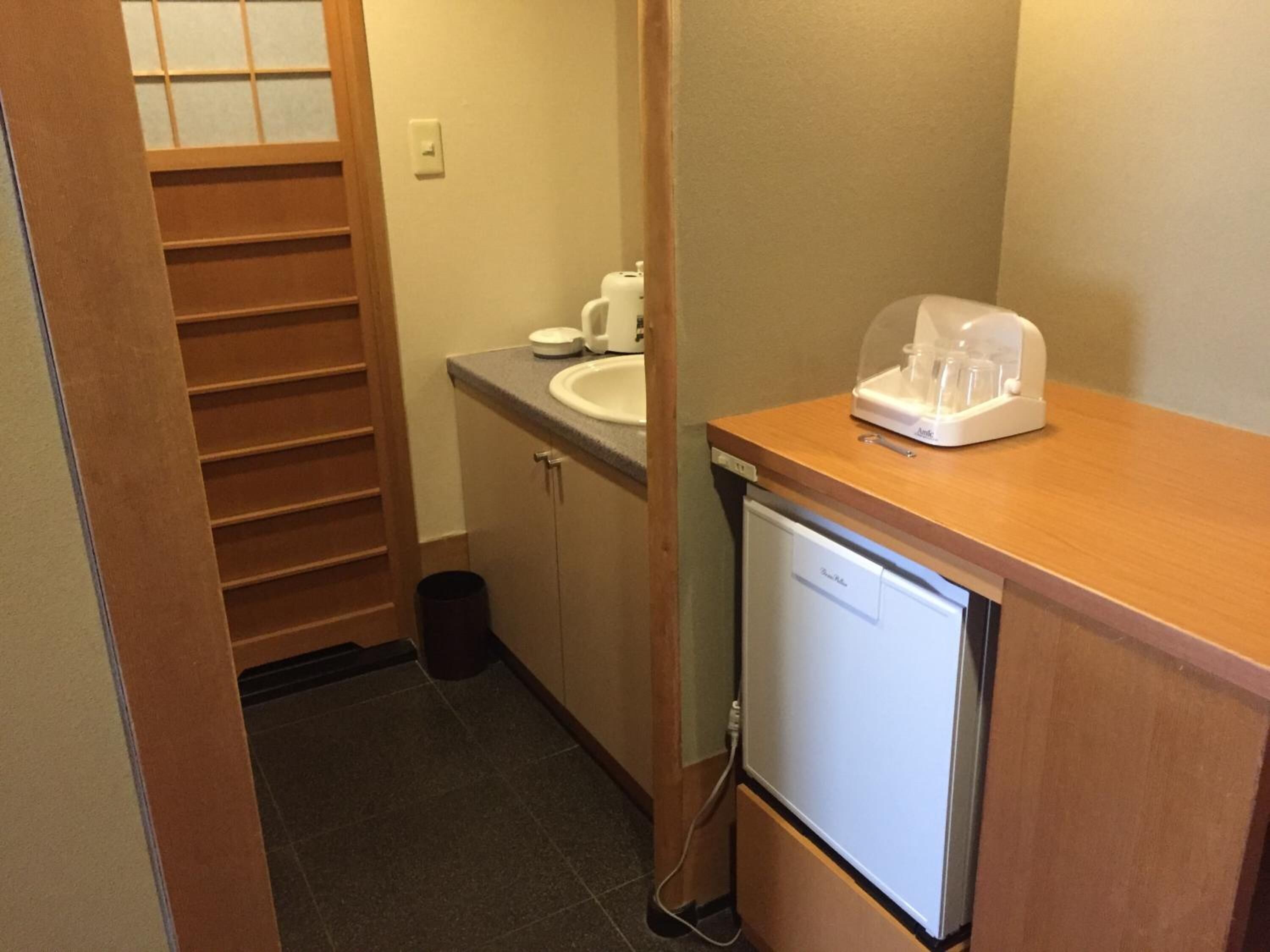 A compact bathroom with a sink, a small refrigerator, and a storage cabinet.