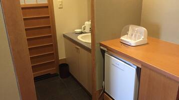 A compact bathroom with a sink, a small refrigerator, and a storage cabinet.