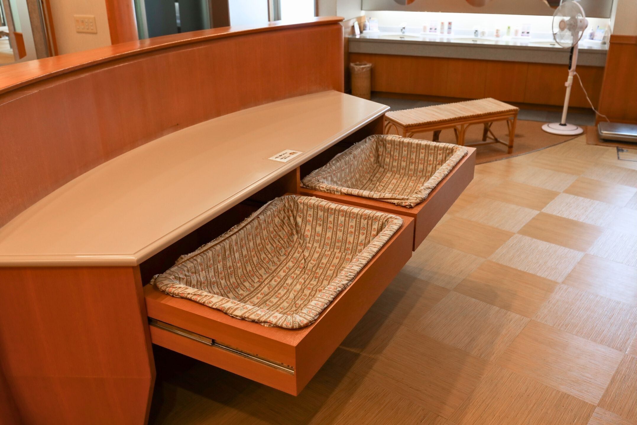 A wooden bench with two woven baskets underneath.