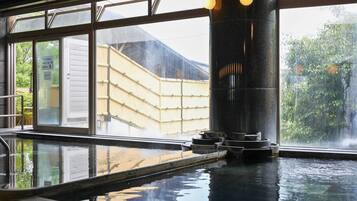 A traditional Japanese onsen with a view of a bamboo fence and a wooden building outside.