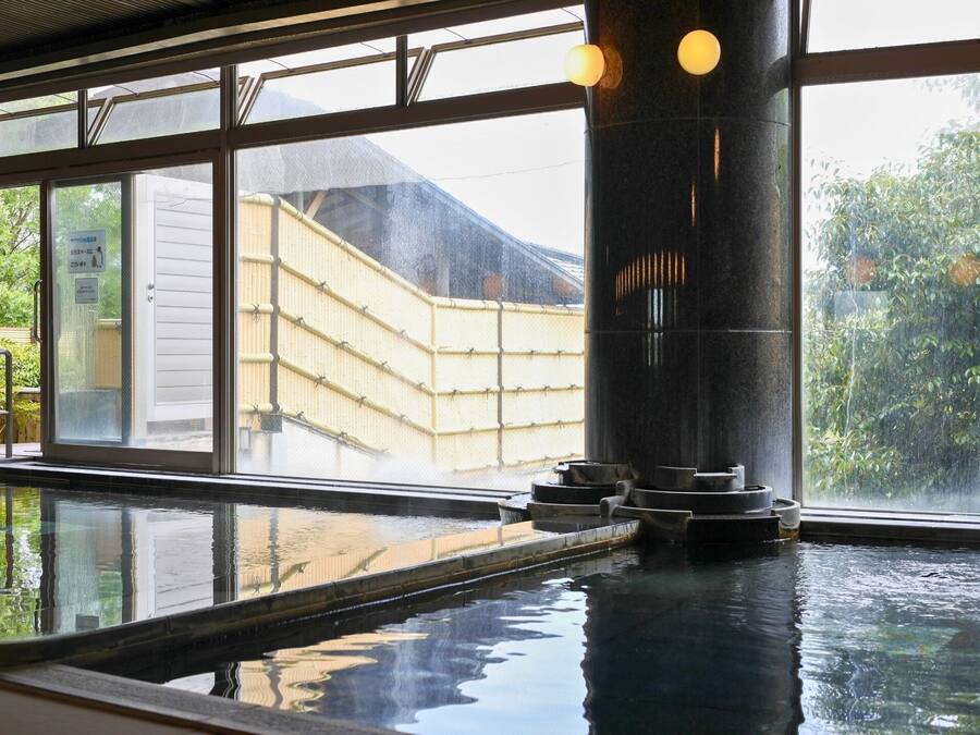 A traditional Japanese onsen with a view of a bamboo fence and a wooden building outside.
