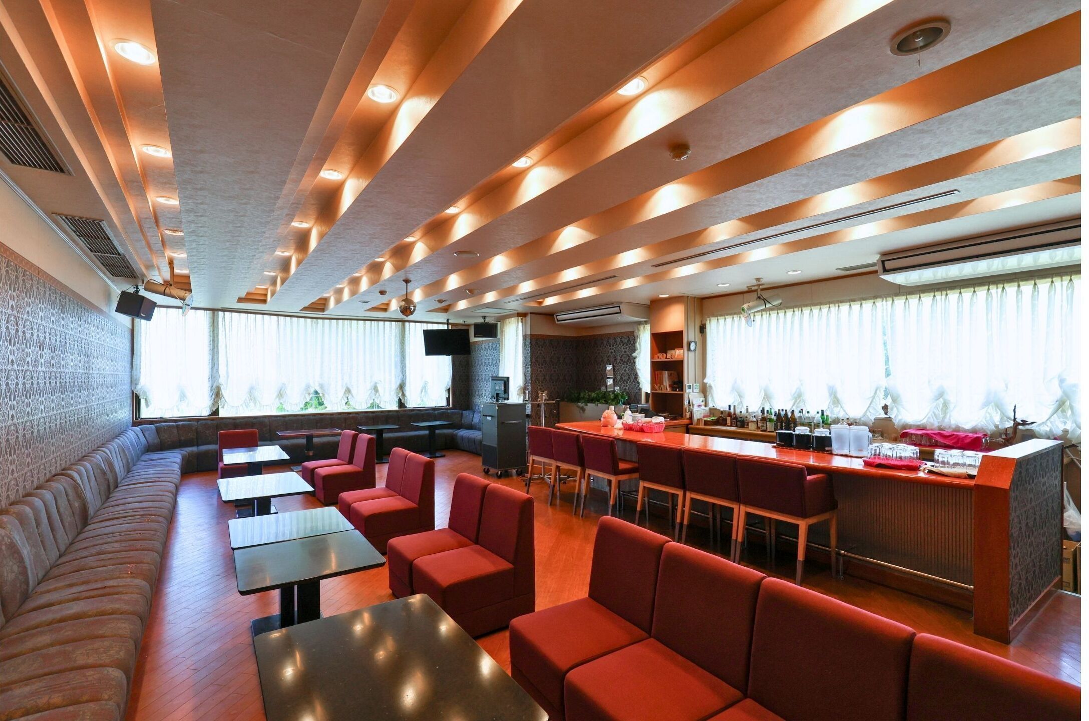A restaurant with a bar area, seating arrangements, and a view of the outdoors.