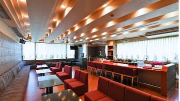 A restaurant with a bar area, seating arrangements, and a view of the outdoors.