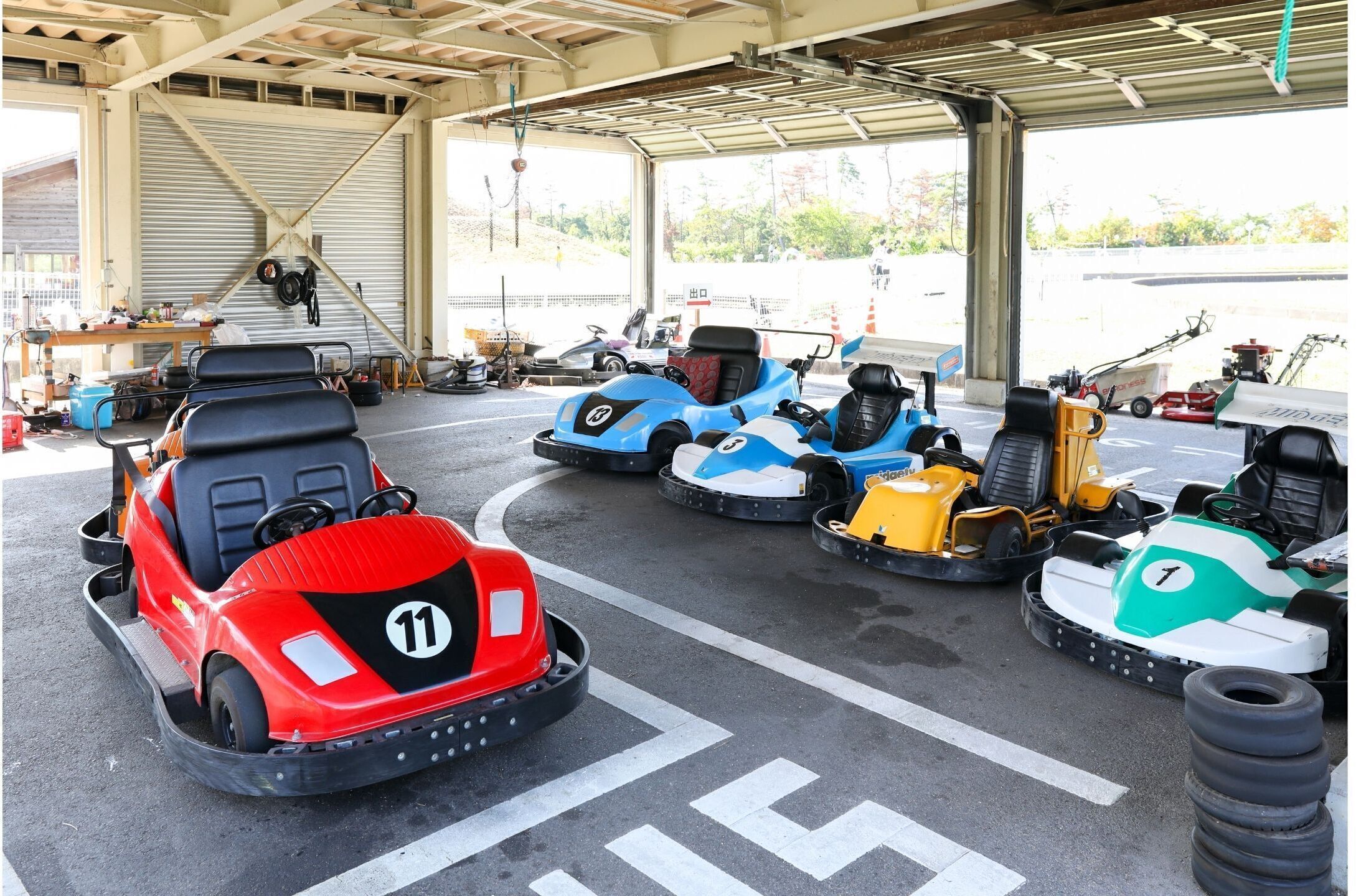 A go-kart track with multiple go-karts and a garage area with tools and equipment.