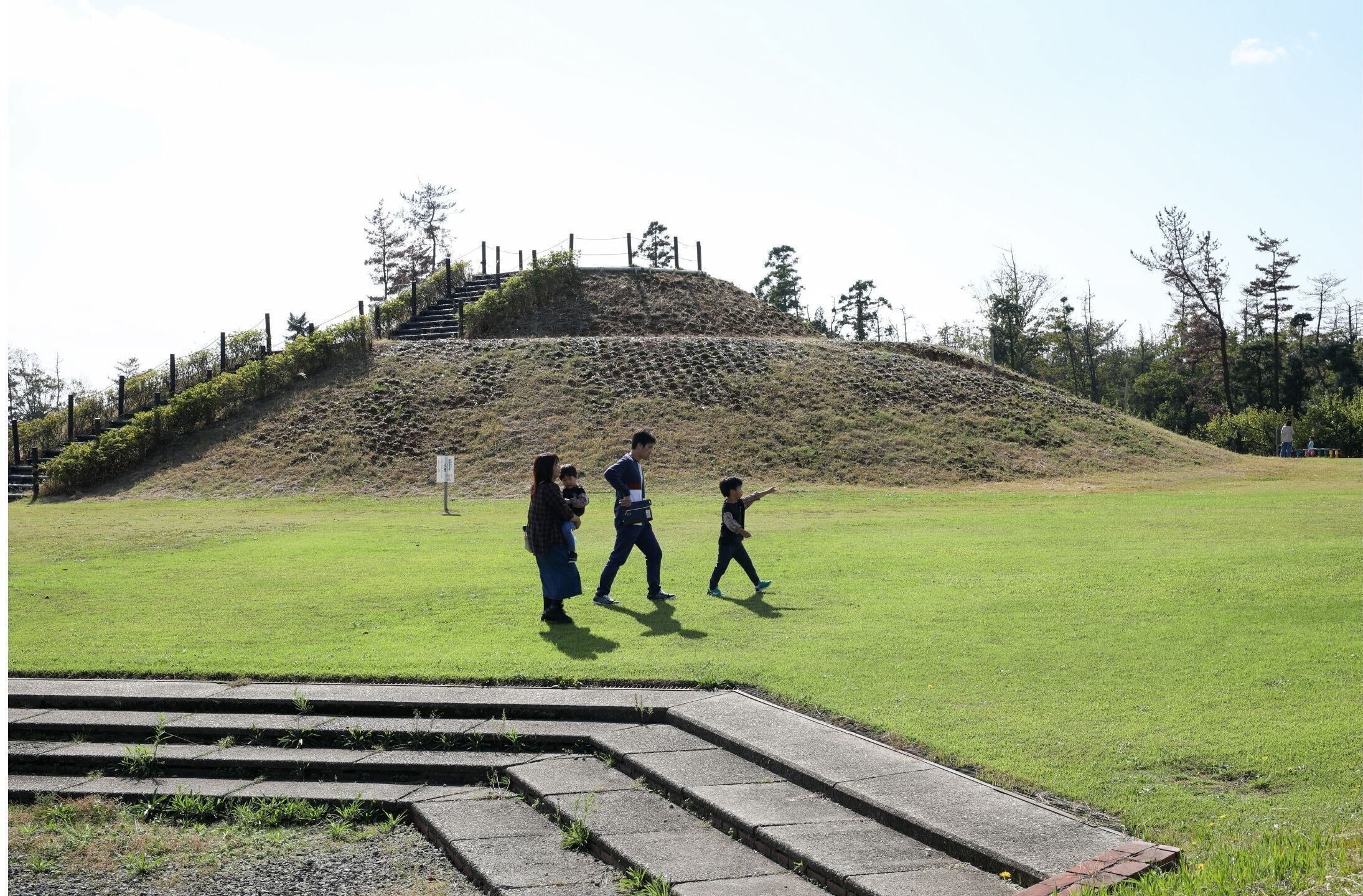 A grassy area with a stone staircase leading up to a hill.