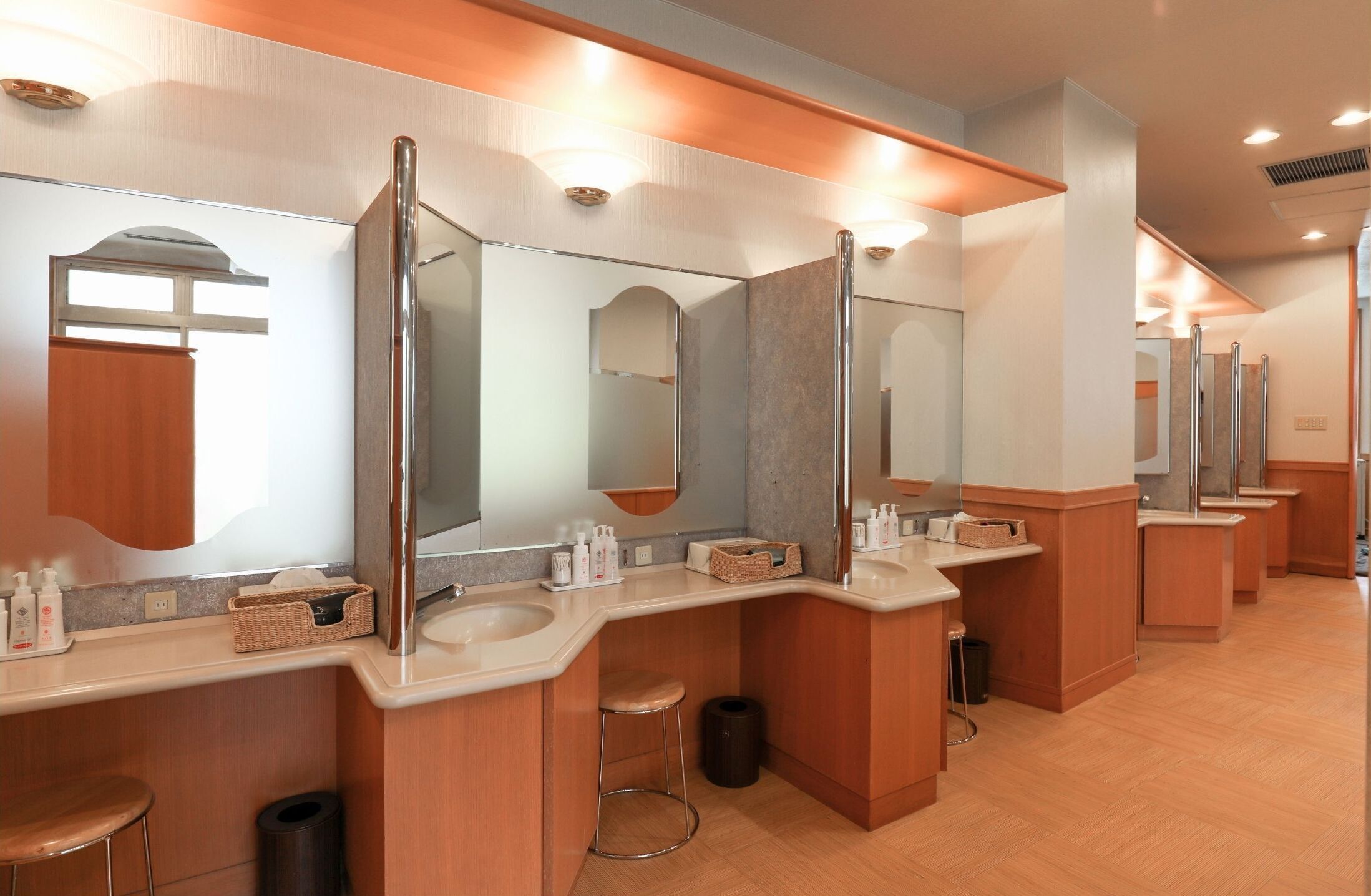 Une salle de bain moderne dotée de plusieurs lavabos, de miroirs et d’un meuble-lavabo en bois.