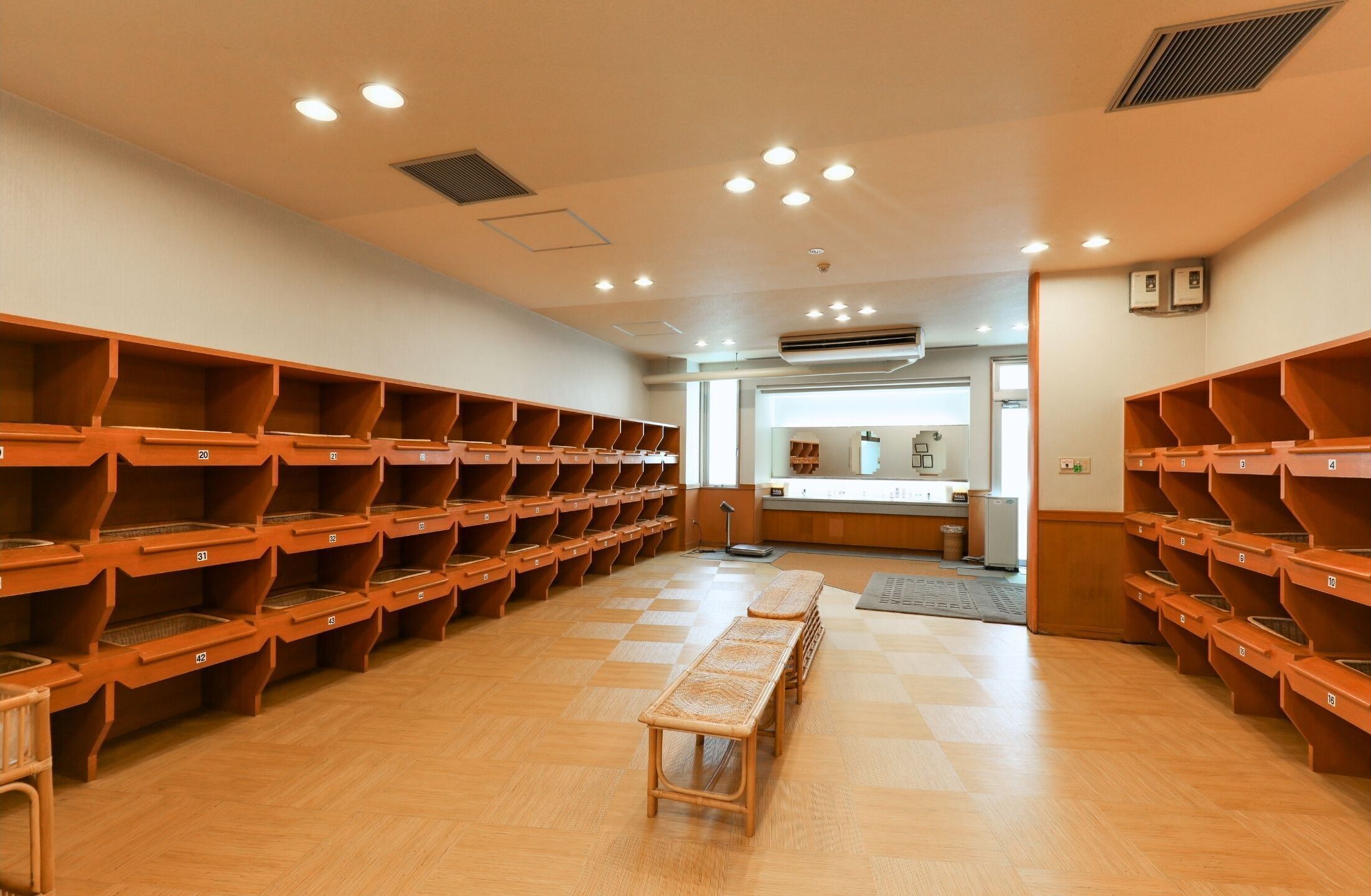 A room with multiple wooden benches and numbered storage bins along the walls.