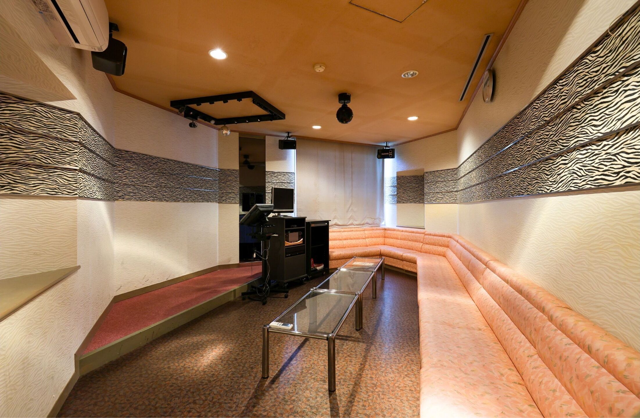 A modern interior with a curved orange sofa, a glass table, and a fireplace.
