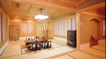 A tatami mat room with a traditional Japanese style, a television, and a sliding door.