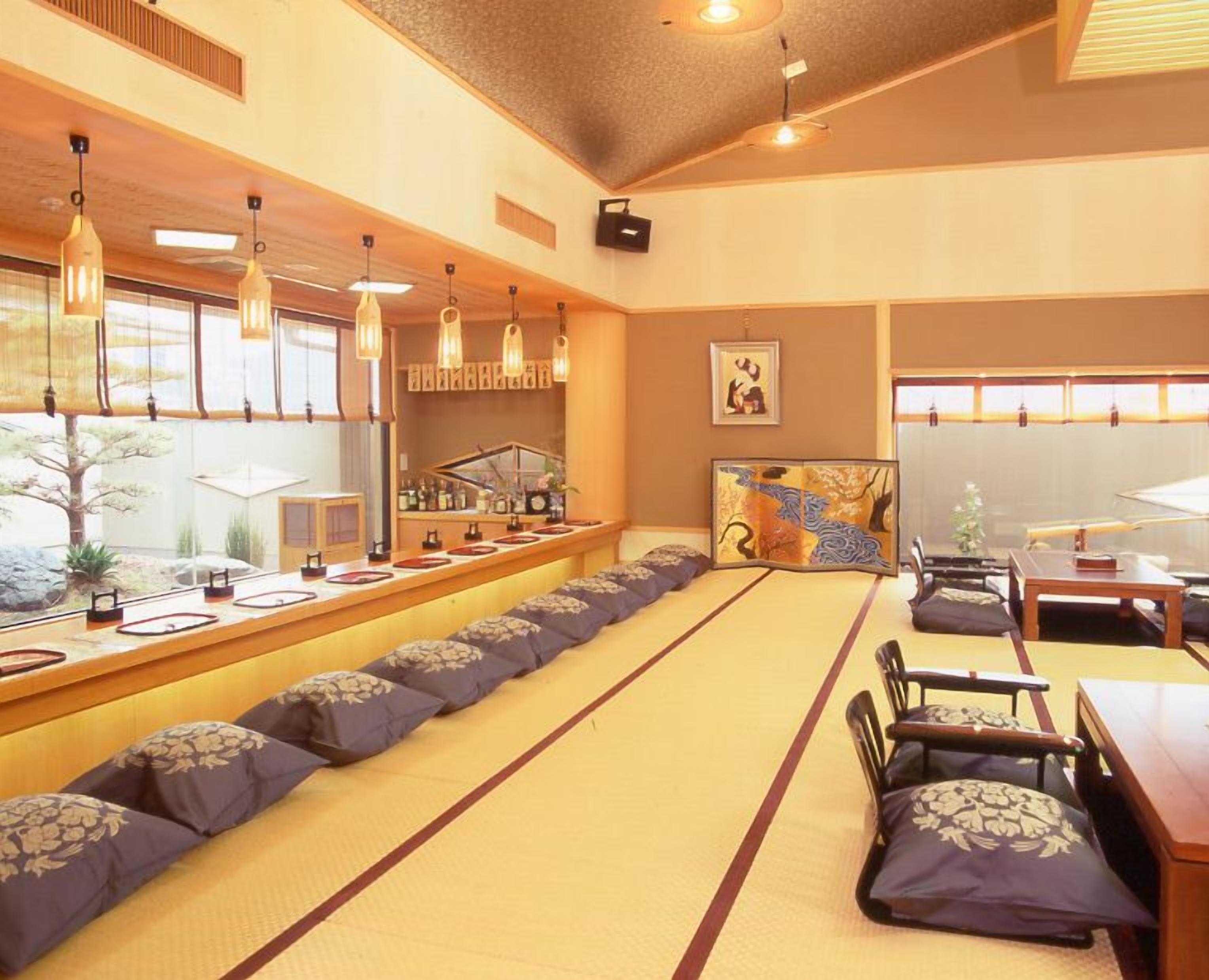 A tatami mat room with a low table, cushions, and a traditional Japanese screen.