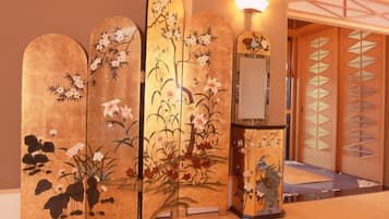 A traditional Japanese room with tatami flooring, a shoji screen, and a decorative wooden screen with floral designs.