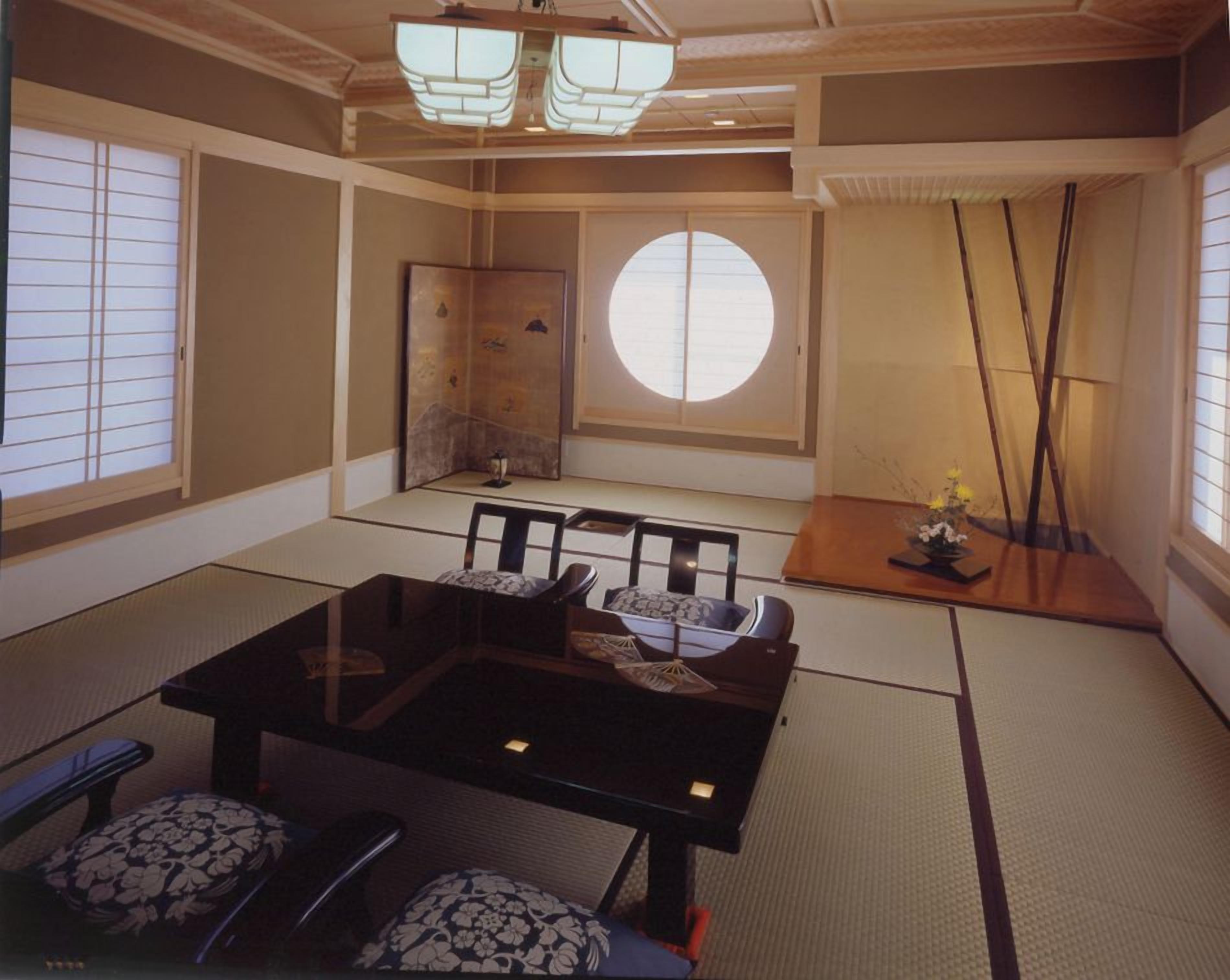 A traditional Japanese room with tatami flooring, a low table with cushions, and sliding doors.