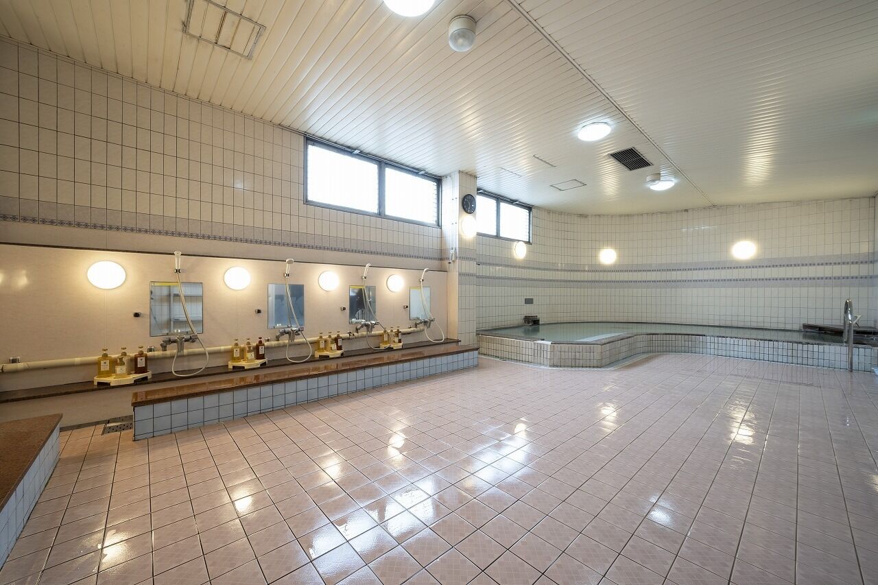 A spacious public restroom with multiple sinks, mirrors, and a large bathtub area.