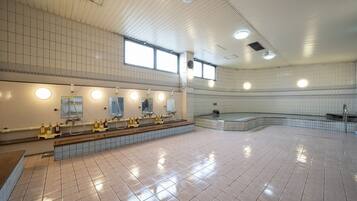 A spacious public restroom with multiple sinks, mirrors, and a large bathtub area.