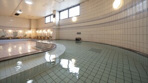 A large indoor swimming pool with multiple lanes, a central island, and a tiled wall with a clock. - Castle Inn Komaki (Komaki)