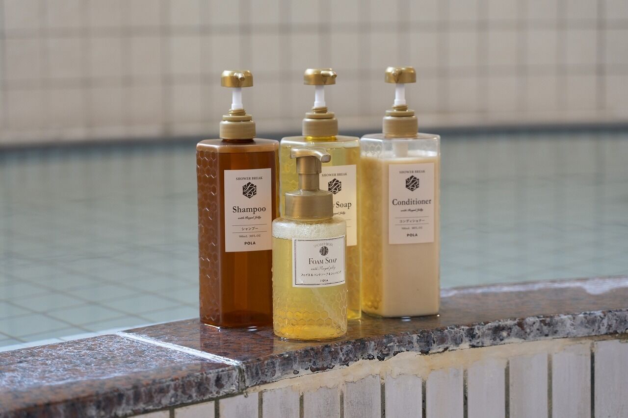 Four bottles of shower products on a tiled ledge.