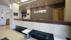 A reception desk with a marble counter, a small seating area, and a wall-mounted sign. - Castle Inn Komaki (Komaki)