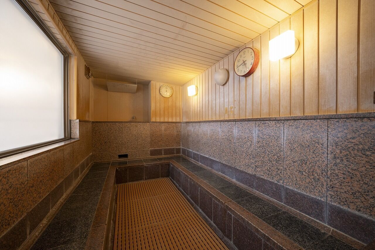 A public sauna with wooden walls, granite tiles, and a wooden floor.
