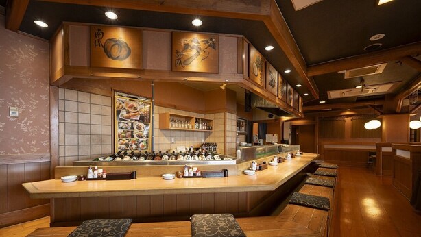 A restaurant with a wooden counter, seating area, and traditional decor. - Castle Inn Komaki (Komaki)
