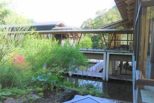 A modern building with a glass facade, a wooden deck, and a water feature in the foreground.