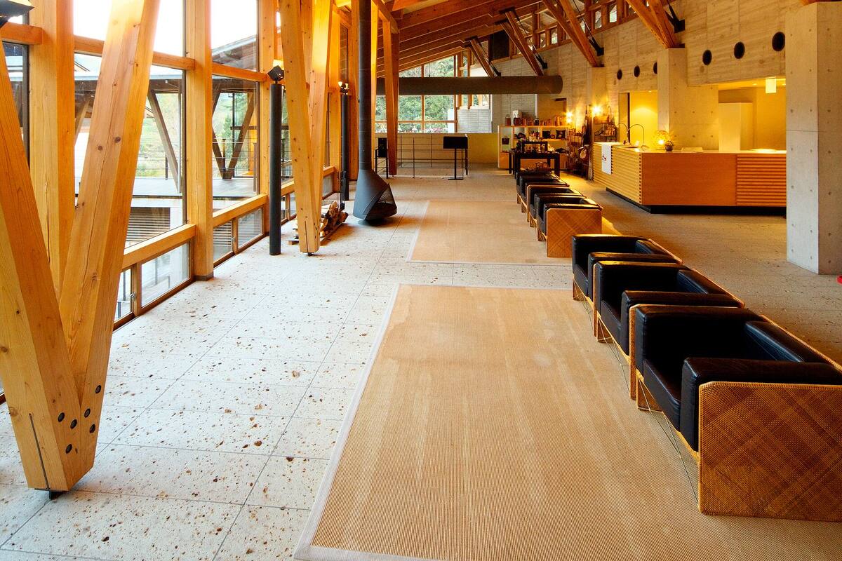 A spacious room with wooden beams, large windows, and a long bench along the wall.