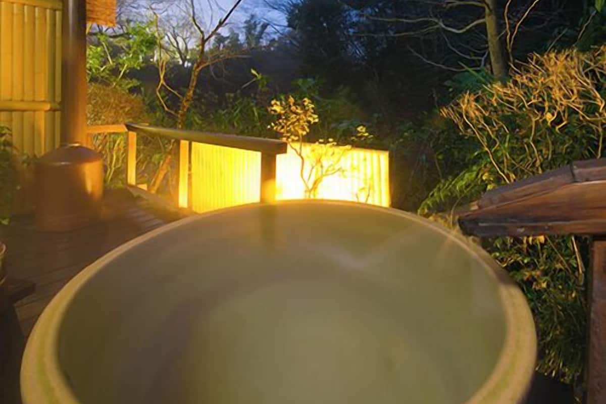 A hot tub in a covered outdoor area with a wooden deck and a brick wall.