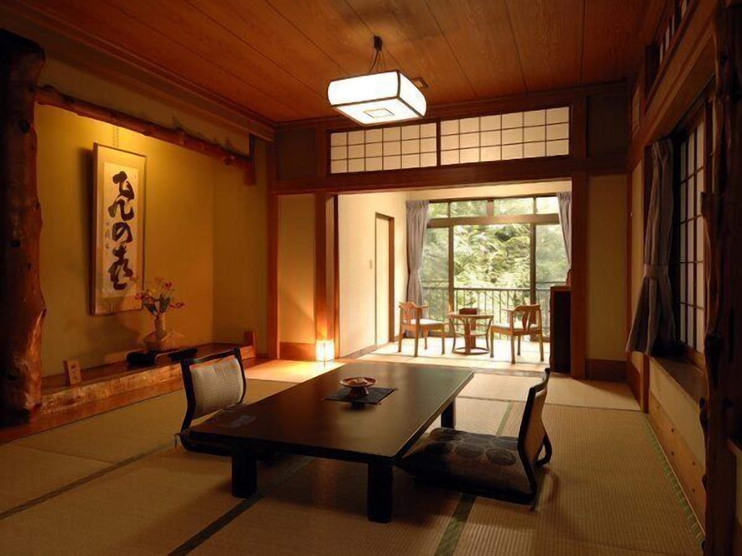 Una habitación japonesa tradicional con suelo de tatami, una mesa baja y puertas correderas que dan a un balcón.