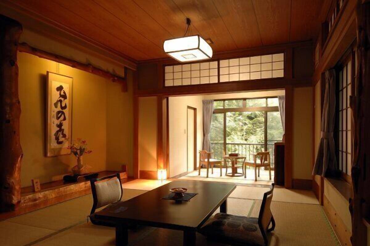 A traditional Japanese room with tatami flooring, a low table, and sliding doors leading to a balcony.