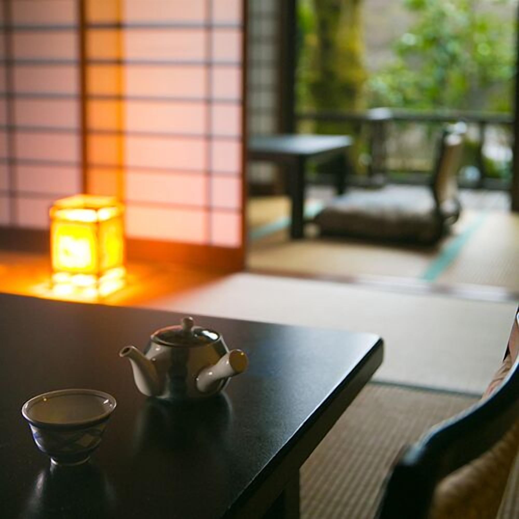 Un tradicional servicio de té japonés con tetera, taza y vela sobre una mesa.