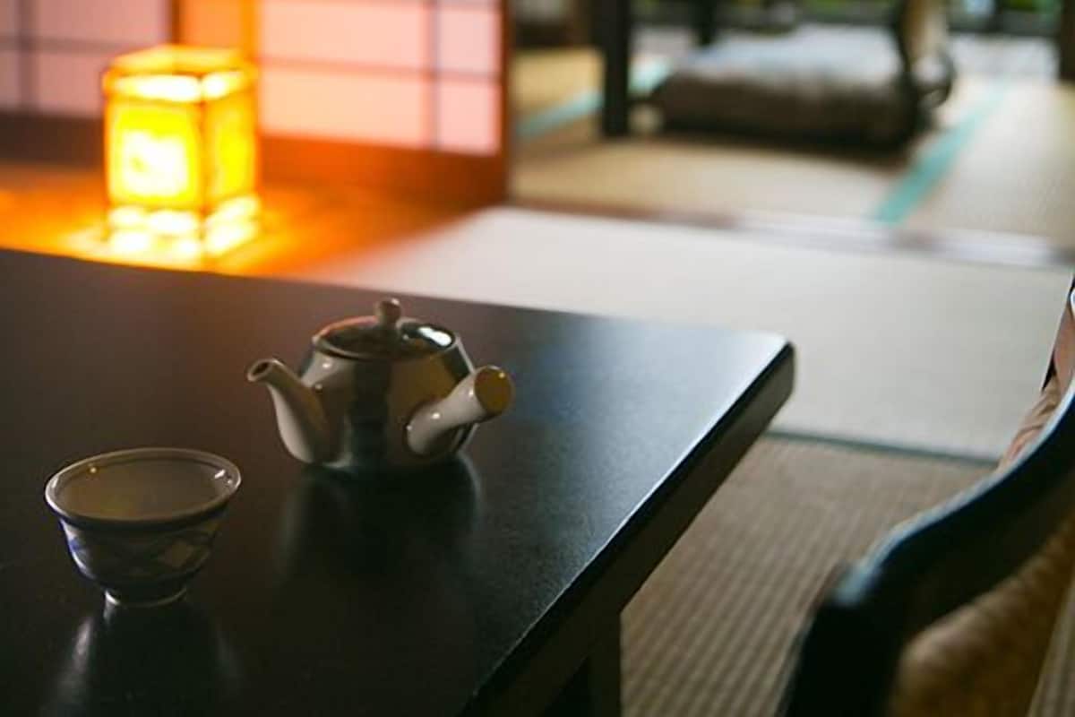 A traditional Japanese tea setting with a teapot, cup, and candle on a table.