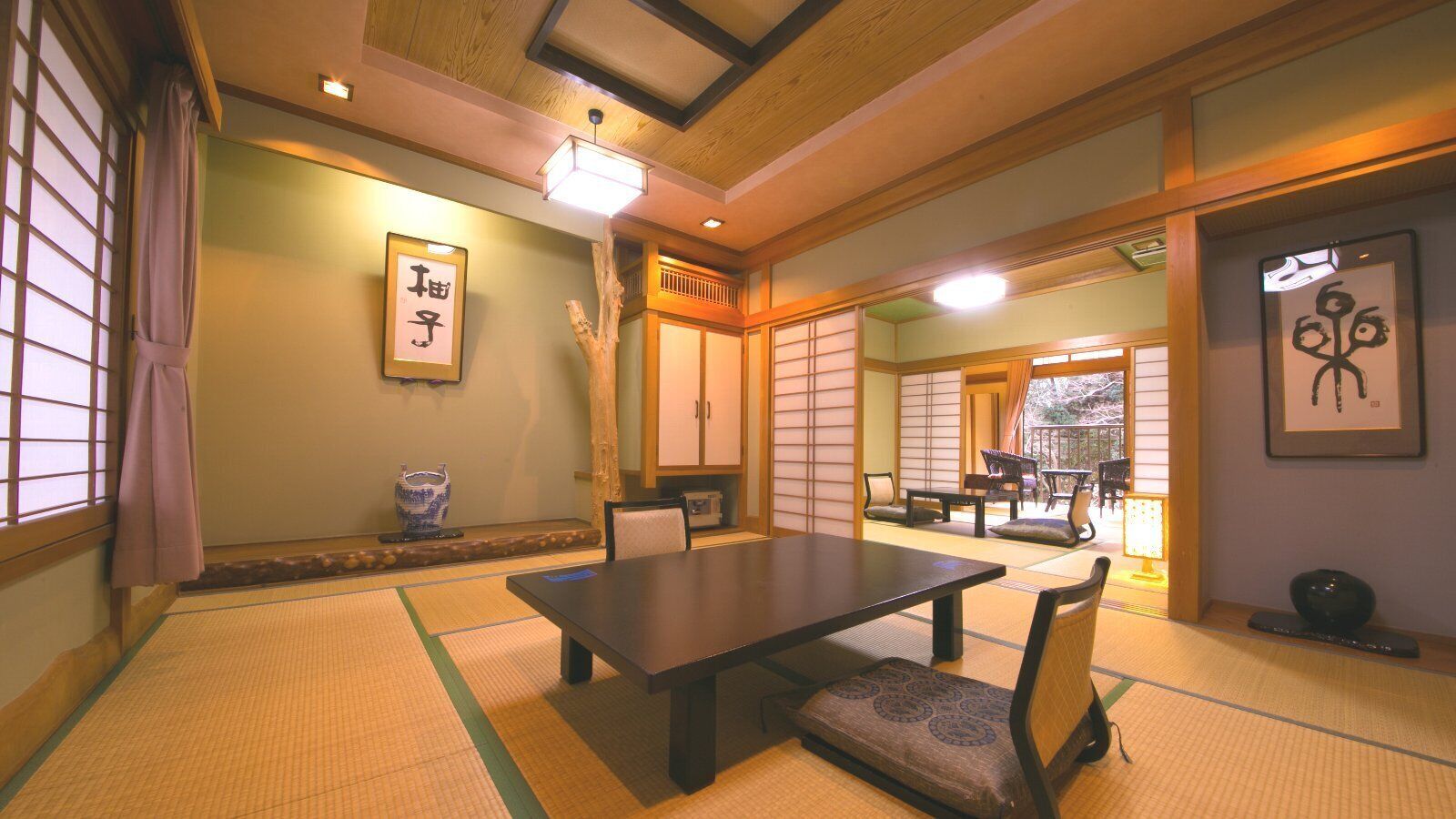 Una habitación japonesa tradicional con suelo de tatami, una mesa baja, sillas y puertas correderas.