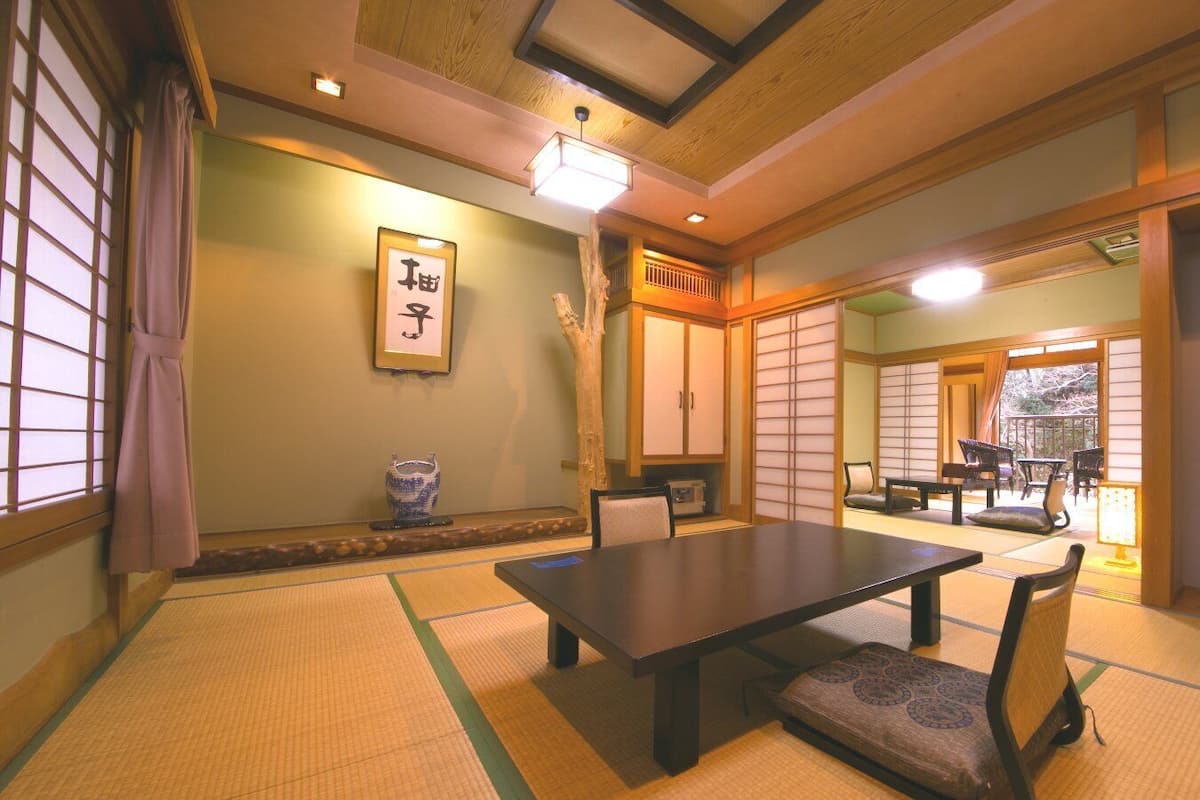 A traditional Japanese room with tatami flooring, a low table, chairs, and sliding doors.