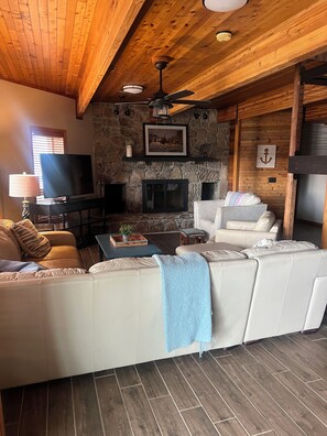 Relax in this inviting space with a comfortable sofa, stone fireplace, and ceiling fan.