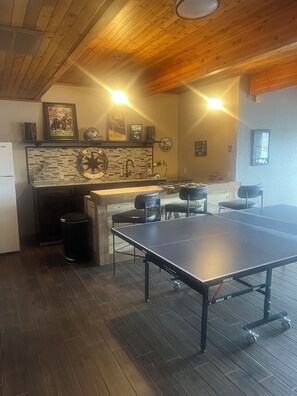 Enjoy a cozy living space with a ping pong table and kitchen area, perfect for relaxation and recreation.