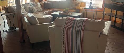 A cozy living room with a sofa, armchairs, a coffee table, and a television.