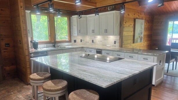 Een moderne keuken met een groot eiland, witte kasten en houten details.