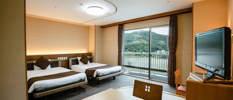 Ein Hotelzimmer mit zwei Betten, einem Fernseher, einem Tisch und Blick auf eine gebirgige Landschaft.