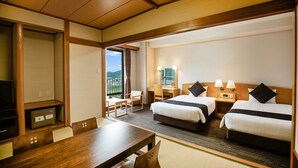 Habitación de hotel con dos camas, un escritorio, una silla, un televisor y vistas al exterior.
