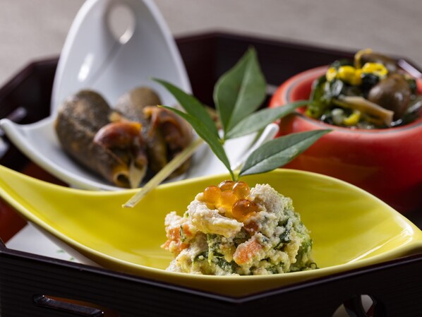 A tray with various dishes including a yellow plate with a seafood dish, a red bowl with vegetables, and a white bowl with meat.