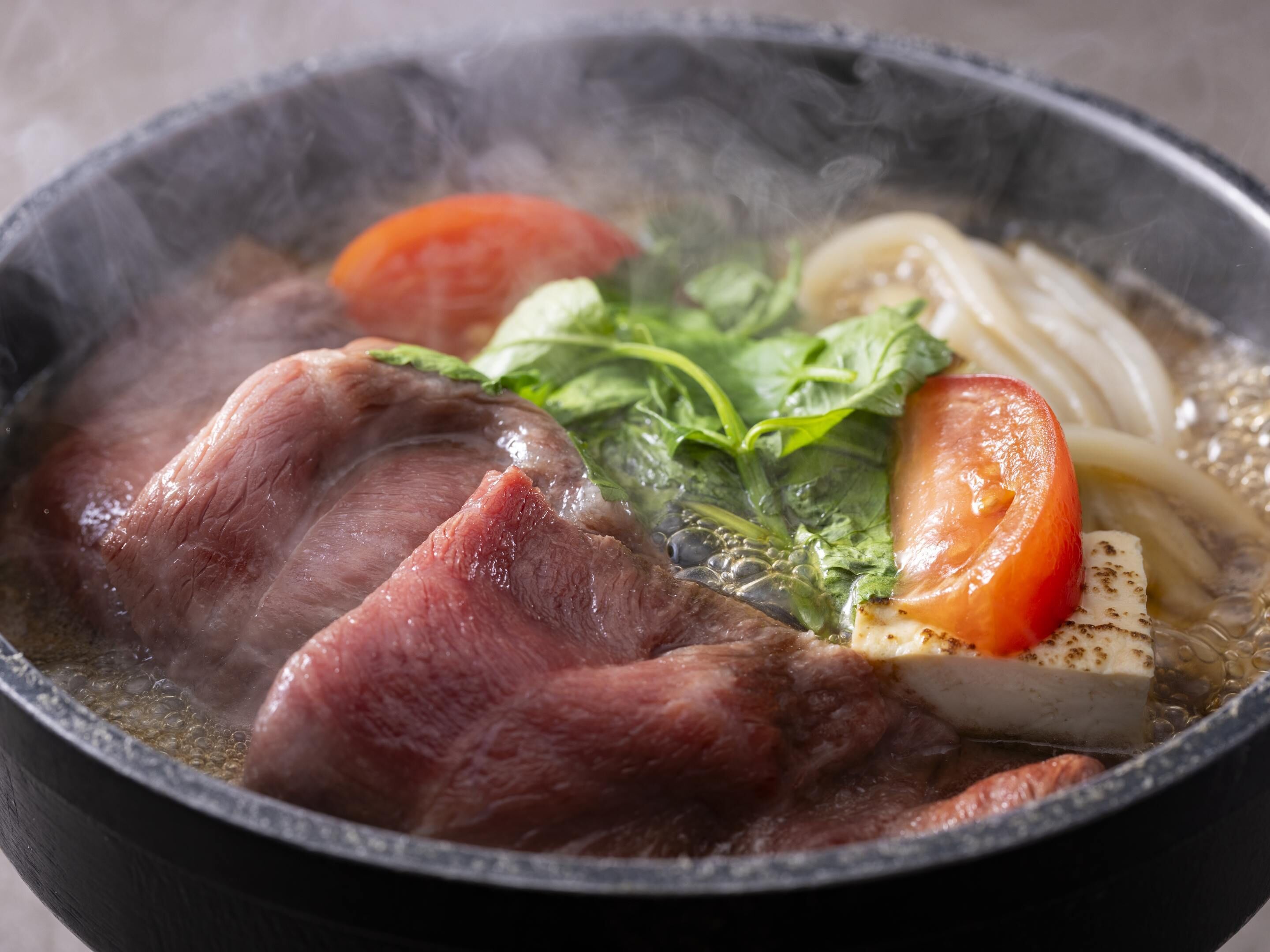 A bowl of soup with meat, vegetables, and noodles.