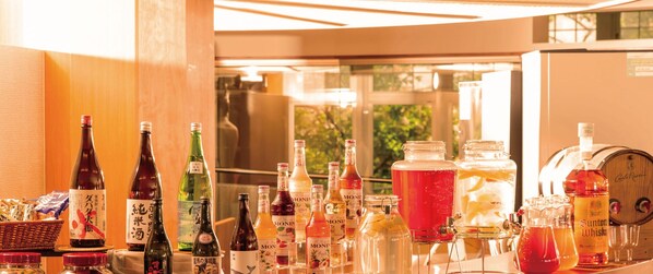 Una zona de bar con varias botellas y vasos de bebidas, incluyendo whisky y otras licores, dispuestas en estantes y mostradores.