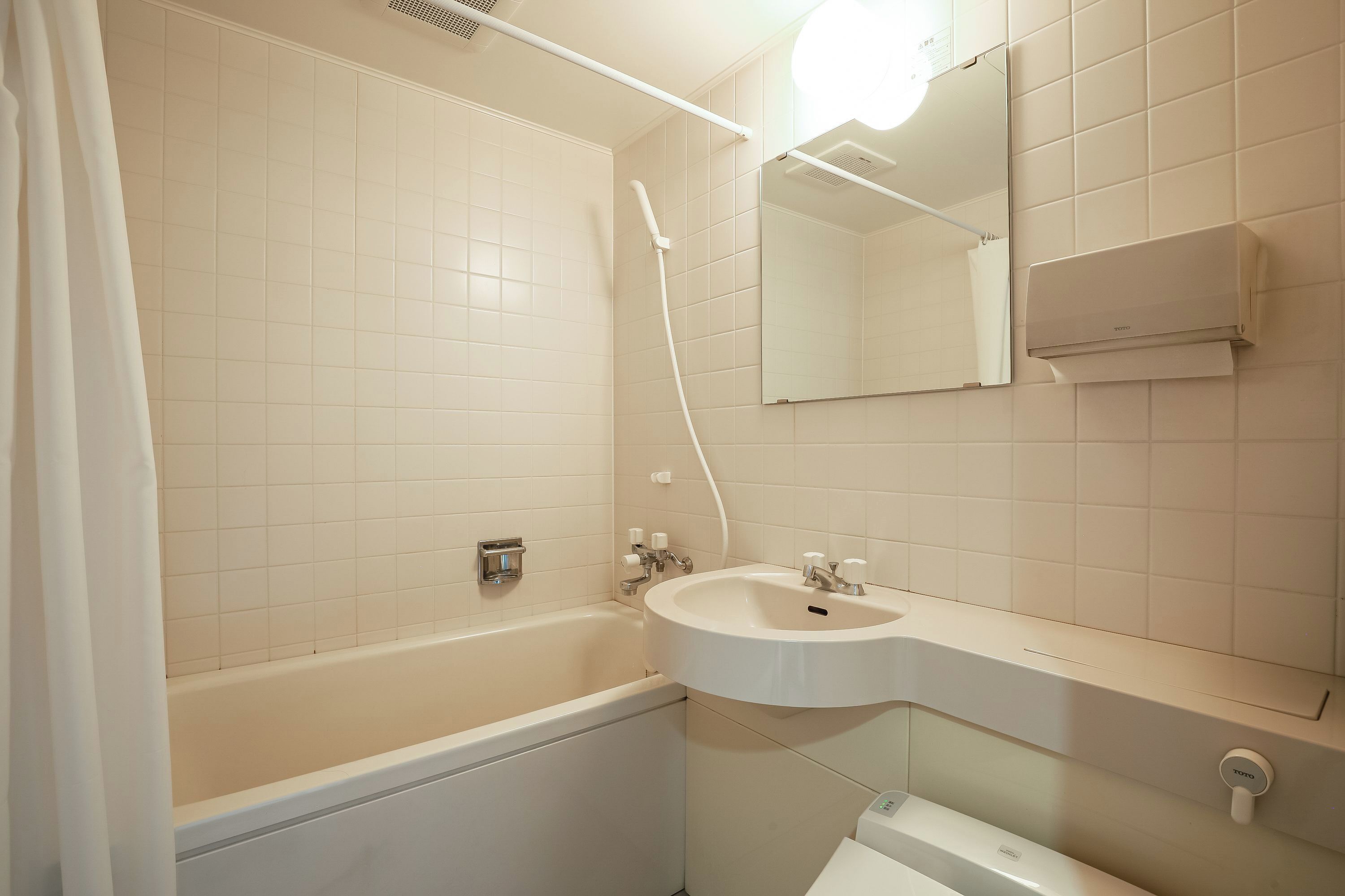 A bathroom with a bathtub, sink, and mirror.
