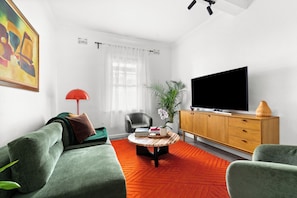A modern living room with a sofa, a television, and a coffee table. - Renovated 3BR Heritage Home  | Private Veranda walk to the Rocks and  Barangaroo (Millers Point)
