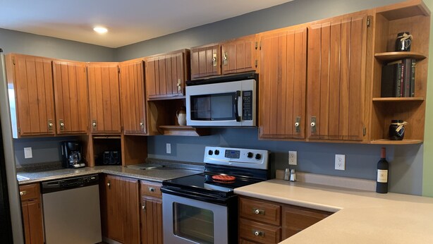 A kitchen with wooden cabinets, a microwave, a stove, and a dishwasher. - 405 S. Madison, Suite A (Watkins Glen)