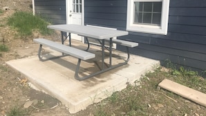 A picnic table with benches in front of a house with a white door and window. - 405 S. Madison, Suite A (Watkins Glen)