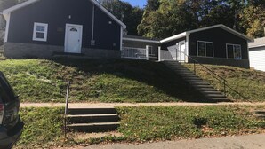 A two-story building with a white door and windows, a small porch, and a staircase leading up to the entrance. - 405 S. Madison, Suite A (Watkins Glen)